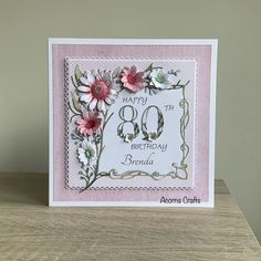 a birthday card with flowers and the number 80 on it, sitting on top of a table