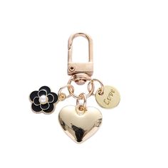 a heart shaped keychain with two charms attached to it's sides and a flower on the other side