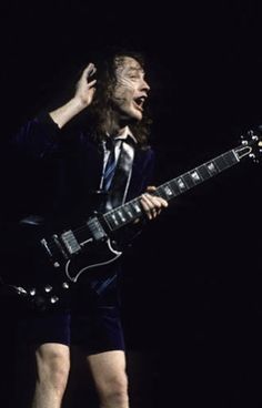 a man with long hair playing an electric guitar