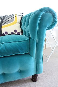 a blue couch sitting on top of a carpeted floor next to a white wall