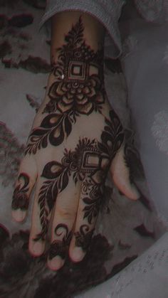 a woman's hand with henna tattoos on it