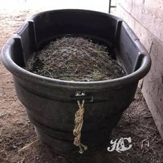 a bucket filled with hay next to a wall