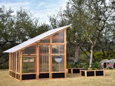 a small greenhouse in the middle of a field with two plants growing out of it