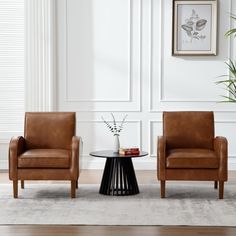 two brown chairs sitting next to each other on top of a rug