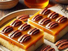 two pieces of cake on a plate with pecans around it and honey in the background