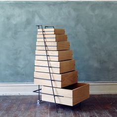 a stack of wooden drawers sitting on top of a hard wood floor next to a wall