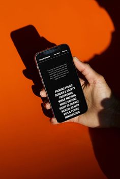 a person holding a cell phone in their hand with the shadow of a man's head on an orange background