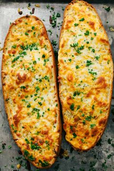 two cheesy breads on a baking sheet with parsley sprinkled on top