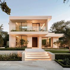 a modern house with stairs leading up to the front door and landscaping on either side