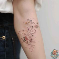 a woman's arm with flowers and stars tattooed on the left side of her arm