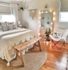 a bed room with a neatly made bed next to a mirror and lights on the wall