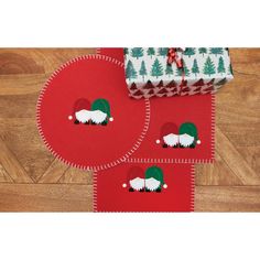 two red placemats with white sheep on them sitting next to a christmas present