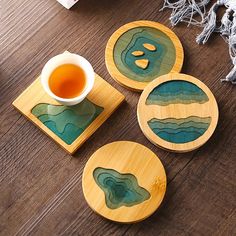 three coasters with designs on them sitting on a wooden table next to a cup of tea