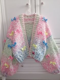 a knitted cardigan hanging on a door with flowers and butterflies all over it