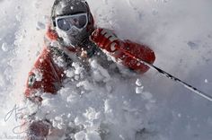 a man riding skis down the side of a snow covered slope with ski poles