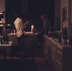 two people standing in a dark kitchen preparing food