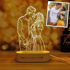 an illuminated photo is shown next to a vase with a flower in it and a couple holding each other