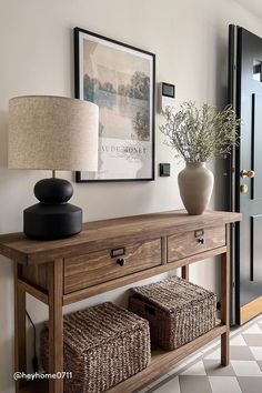 a wooden table with two baskets on top of it next to a lamp and door