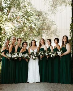 a group of women standing next to each other wearing green dresses and holding bouquets