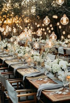 a long table with white flowers and hanging lights