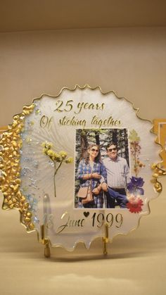 a 25th wedding anniversary photo frame with flowers and leaves on the front, in gold