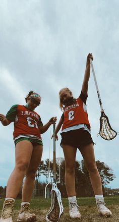 two female lacrosse players are holding their racquets