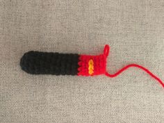 a crocheted red and black object with a yellow light on it's end