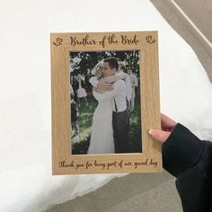 a person holding up a wooden frame with a picture of a bride and groom on it