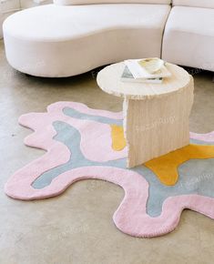 a white couch sitting next to a table on top of a rug in a living room