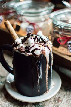 a hot chocolate drink with marshmallows and cinnamon sticks in the top, sitting on a saucer