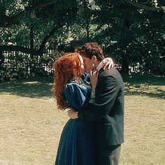 a man and woman are kissing in the grass