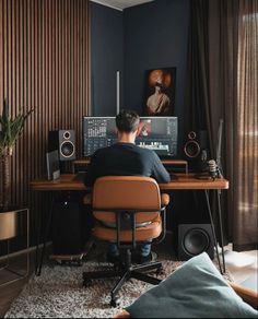 a man sitting at a desk in front of a computer monitor with speakers on it