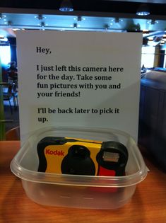 a plastic container with a yellow and black object in it's lid that says hey, i just let this camera here for the day take some fun pictures with you and your friends