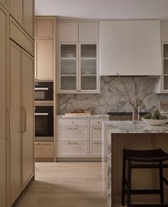 a kitchen with white cabinets and marble counter tops, along with an island in the middle