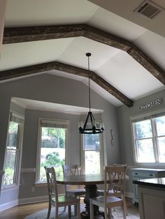 the dining room table is surrounded by four chairs and has a chandelier hanging from the ceiling