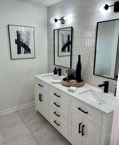 a bathroom with two sinks, mirrors and pictures on the wall