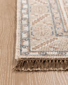 a close up of a rug on the floor with wood floors and white walls in the background