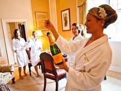 a group of women in bath robes holding up a bottle of champagne while standing next to each other