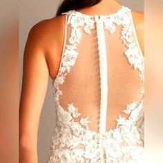 the back of a woman's wedding dress with white lace and flowers on it