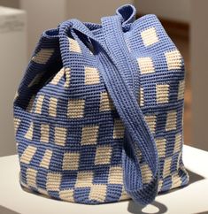 a crocheted blue and white bag sitting on top of a table next to a wall