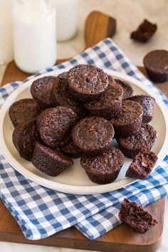 a white plate topped with chocolate muffins on top of a table next to a glass of milk