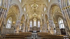 the inside of a church with pews and chandeliers