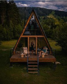 two people sitting on chairs in front of a cabin