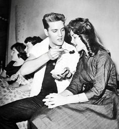 an old black and white photo of a man helping a woman put on her tie