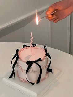 a person lighting a candle on top of a cake with black ribbon around the edges