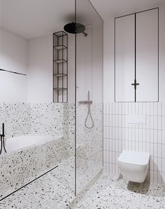 a white bathroom with black and white tile on the floor, shower stall and toilet