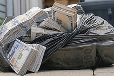 a pile of money sitting on top of a trash can next to a garbage can