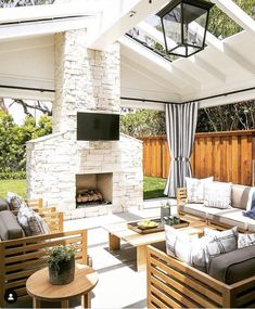 an outdoor living area with couches, chairs and a fire place