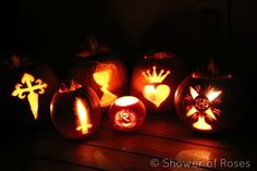 carved pumpkins with lit candles in the shape of hearts, crosses and hands on them