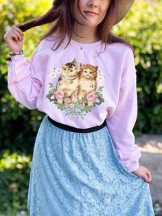 This is the Vintage Kitten Crewneck Sweatshirt. The soft, warm material is made from a blend of cotton and polyester. It has no itchy side seems and a trendy, loose fit. The cool design on this cottagecore crewneck features a collage of vintage kitty and flower illustrations salvaged from old books and ephemera. PLEASE SIZE UP 2-3 SIZES FOR A TRENDY, LOOSE FIT! This design is created by Jillian Anderson @ A Living Whimsy. She uses digital graphic design elements and collage and optimizes each im Pink Long Sleeve Tops With Cat Design, Casual Sweatshirt With Cat Print In Relaxed Fit, Pink Long Sleeve Top With Cat Design, Casual Relaxed Fit Sweatshirt With Cat Print, Casual Cat Print Sweatshirt In Relaxed Fit, Cottagecore Crew Neck Graphic Print Top, Cottagecore Cotton Crew Neck Sweatshirt, Cottagecore Sweatshirt, Cotton Crew Neck Sweater With Cat Design